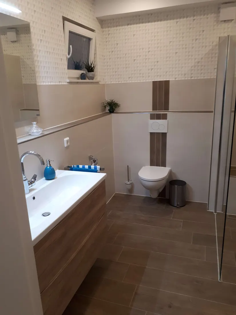 Modernes Bad mit Waschtisch in Holzoptik und wandhängendem WC